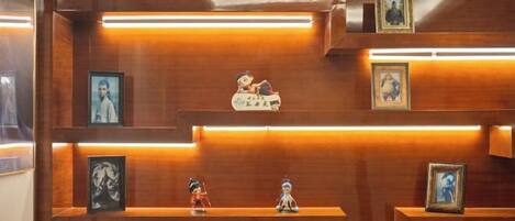 A wooden wall with multiple shelves displaying framed pictures and figurines.