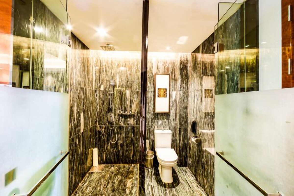 A modern bathroom with a glass shower enclosure, a marble wall, and a toilet.