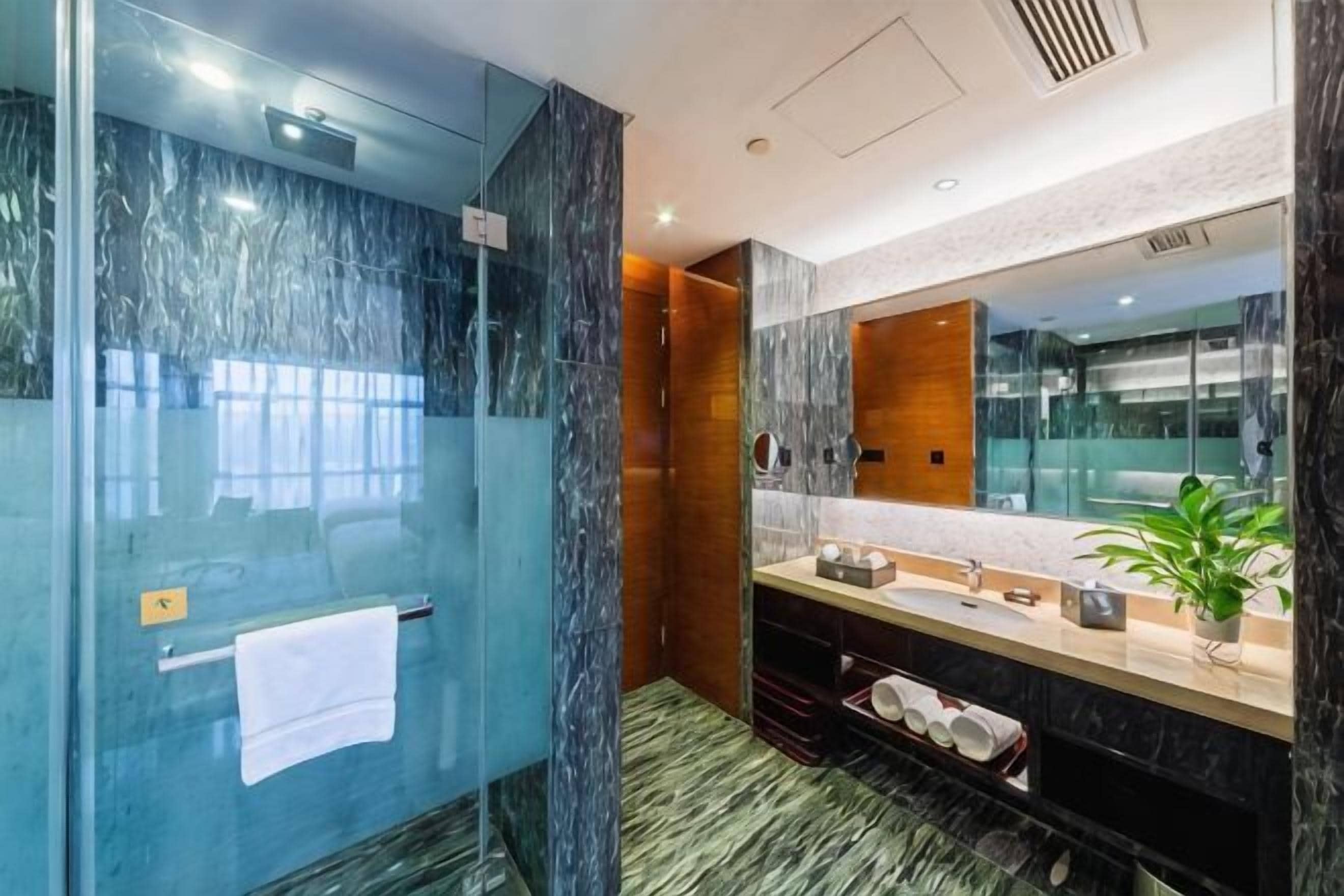 Un baño moderno con ducha de vidrio, tocador de madera y un espejo grande.