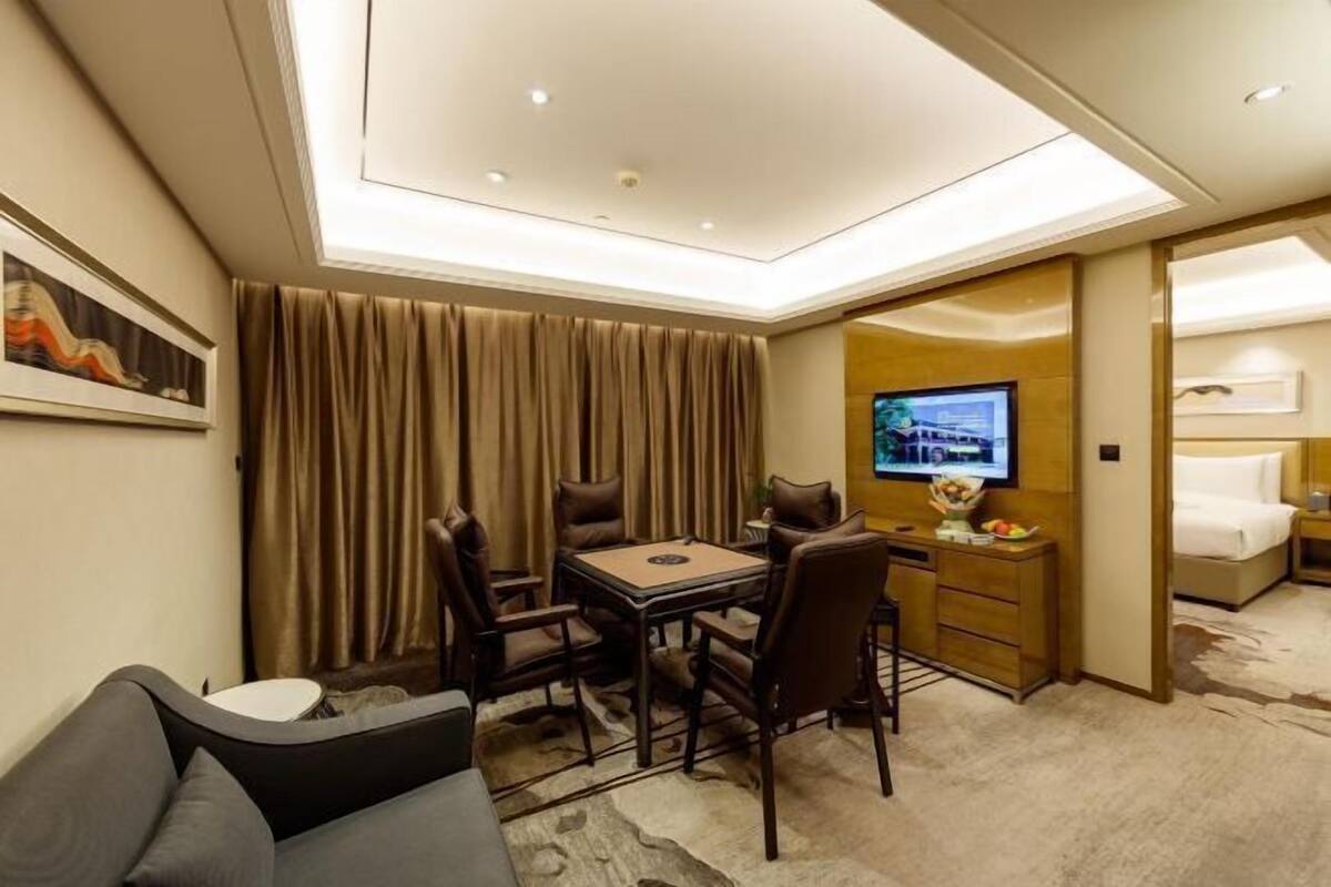 A hotel room with a dining area, a television, a bed, and a sofa.