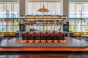 A bar area with a central bar counter, multiple seating options, and a large window with a view of greenery.