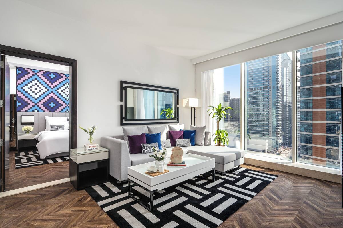 A modern living room with a sofa, coffee table, and a large window with a city view.