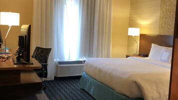 Ein Hotelzimmer mit Bett, Schreibtisch, Stuhl und zwei Nachttischlampen.