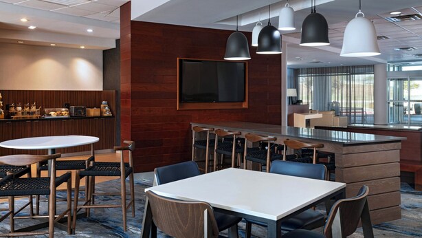 Un hall d’hôtel moderne doté d’un bar, de différents espaces de détente et d’un grand écran de télévision.