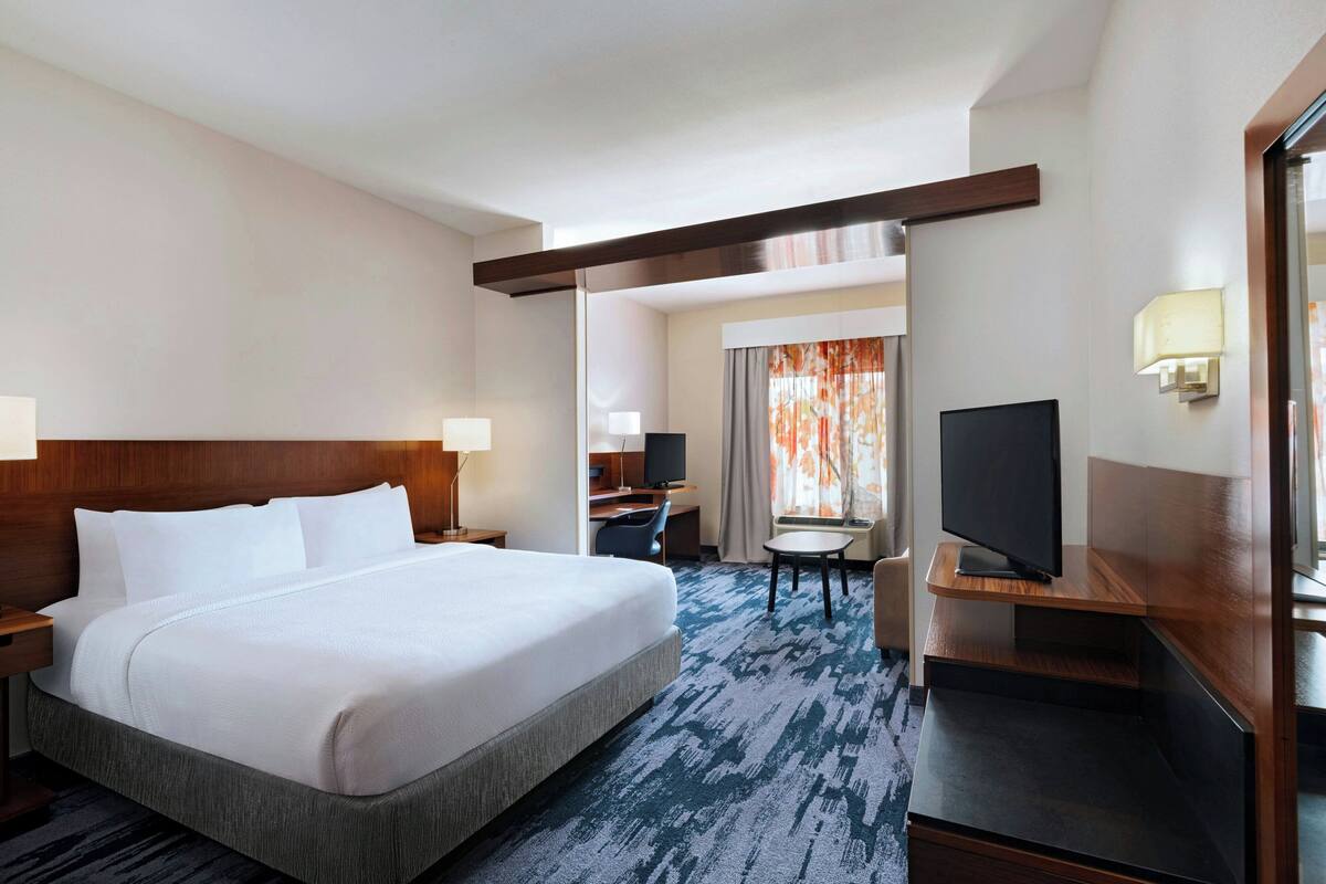 A hotel room with a large bed, a desk, a television, and a small table.