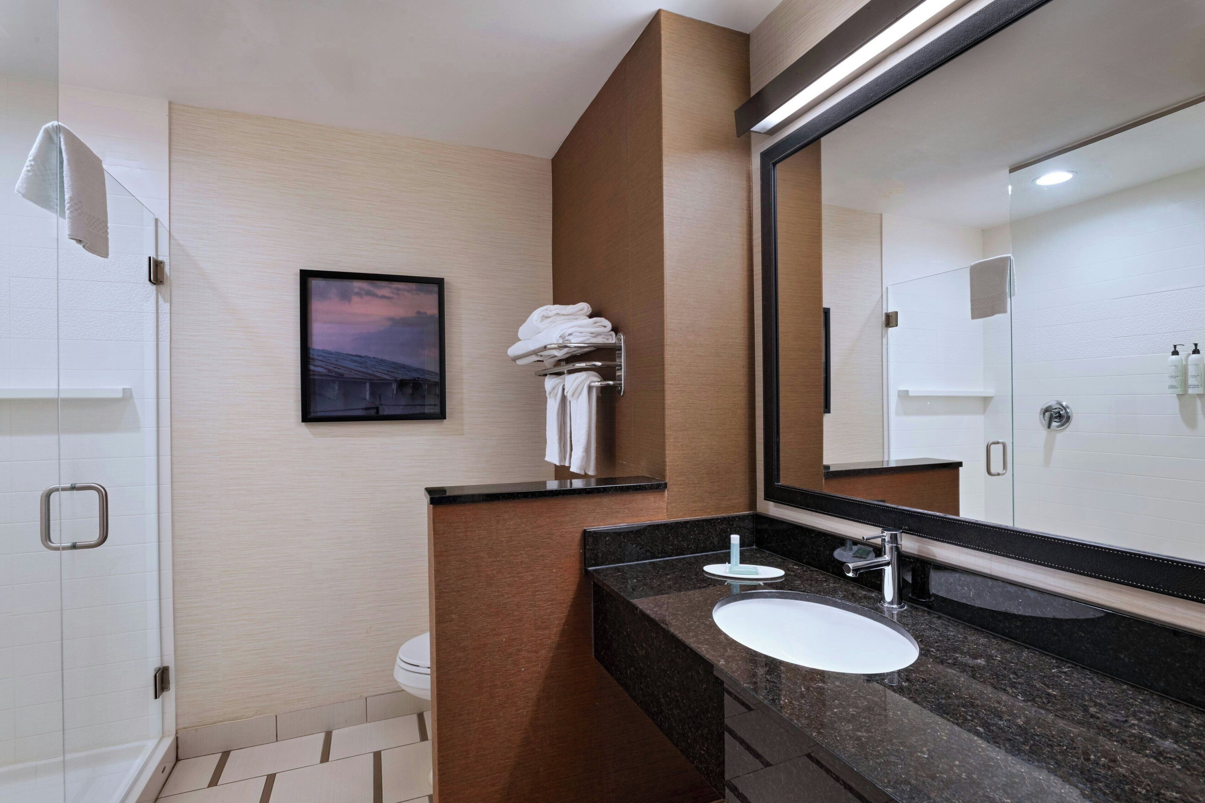 Un bany modern amb un mirall gran, un lavabo i una dutxa.