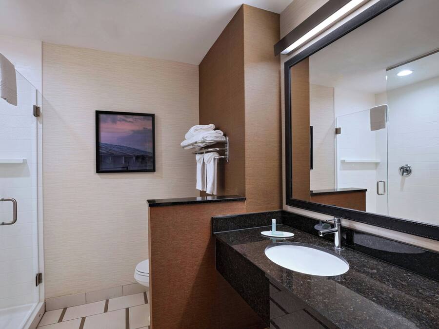 A modern bathroom with a large mirror, a sink, and a shower.