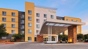 Un hôtel Fairfield by Marriott doté d’une entrée moderne, de plusieurs étages et d’une structure en piliers de pierre.