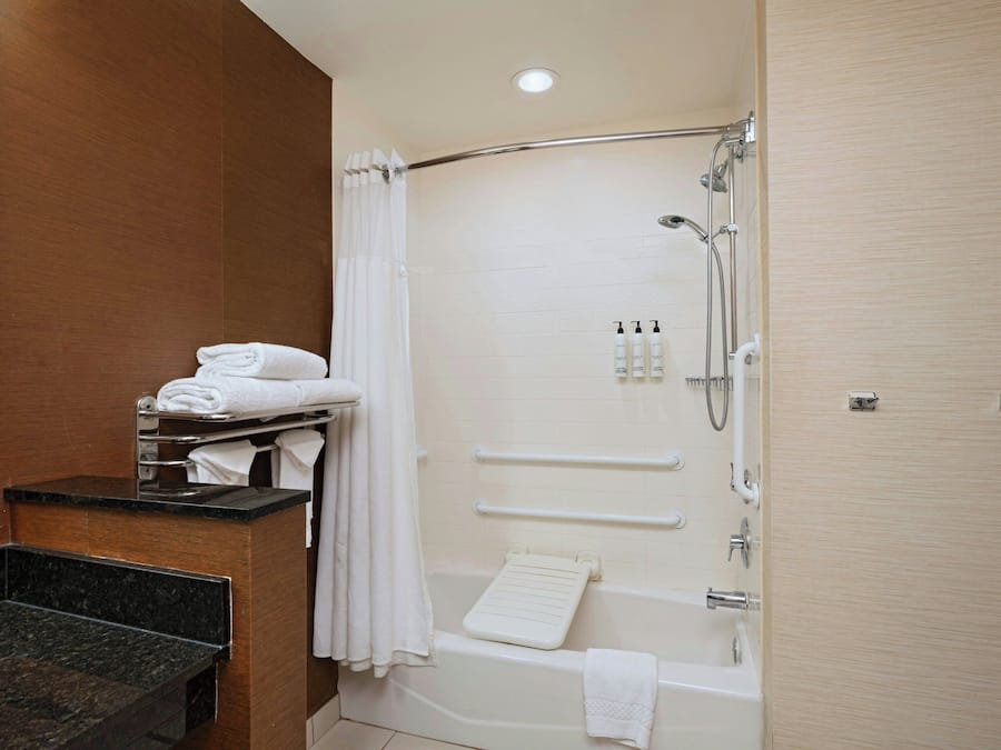 Een moderne badkamer met douche, bad en een wastafel met spiegel.