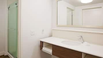 A bathroom with a white sink, a mirror, and a glass shower door.
