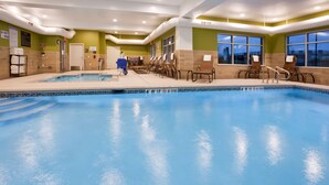 A swimming pool with lounge chairs and a lifeguard chair, surrounded by green walls and large windows. - Hampton Inn Minneapolis Bloomington West (Bloomington)