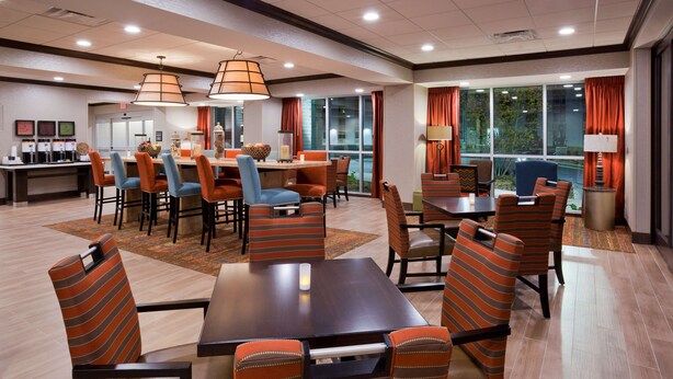 A hotel dining area with striped chairs, a central table, and pendant lighting. - Hampton Inn Minneapolis Bloomington West (Bloomington)
