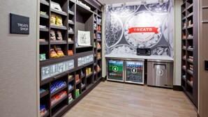 A treats shop with shelves stocked with various snacks and a refrigerated display case. - Hampton Inn Minneapolis Bloomington West (Bloomington)