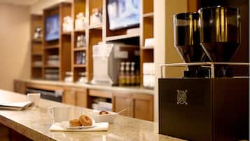 A kitchen counter with a coffee machine, a bowl of cereal, and a cup.