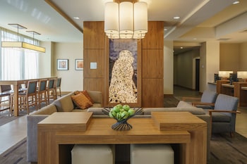 A modern indoor pool area with clear glass walls, lounge chairs, and a view of the cityscape. at Hyatt Place Houston/Galleria