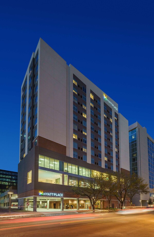 Un hôtel à plusieurs étages au design moderne, avec une enseigne « Hyatt Place » bien visible sur la façade et une entrée bien éclairée.