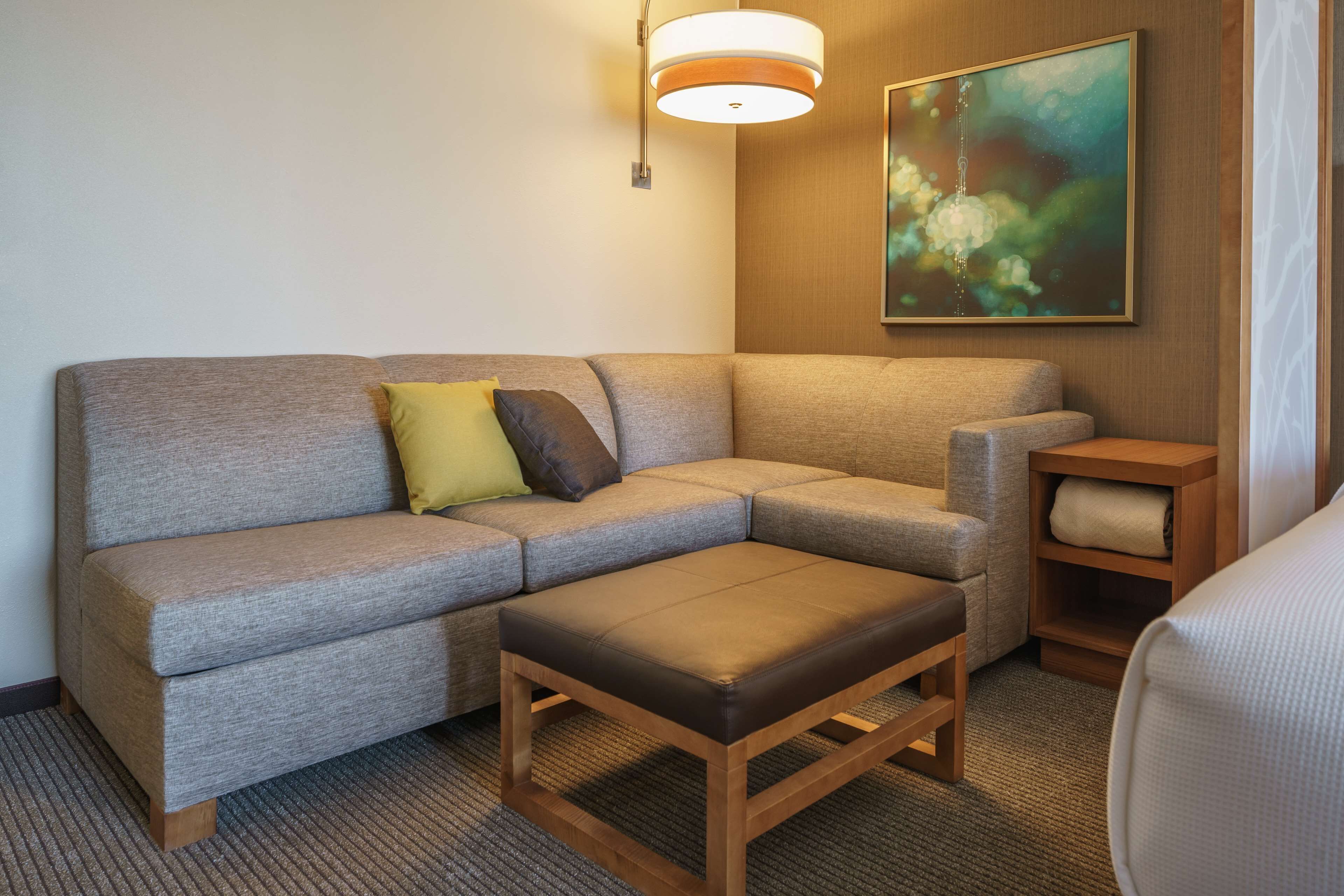 A modern living room with a grey sofa, a wooden coffee table, and a painting on the wall.