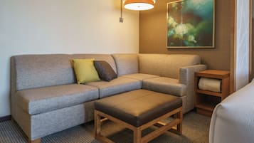 Uma sala de estar moderna com um sofá cinzento, uma mesa de centro de madeira e um quadro na parede.
