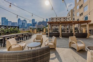 An outdoor seating area with wicker furniture, a pergola, and a city skyline view. - Hotel Indigo Austin Downtown - University by IHG (Austin)
