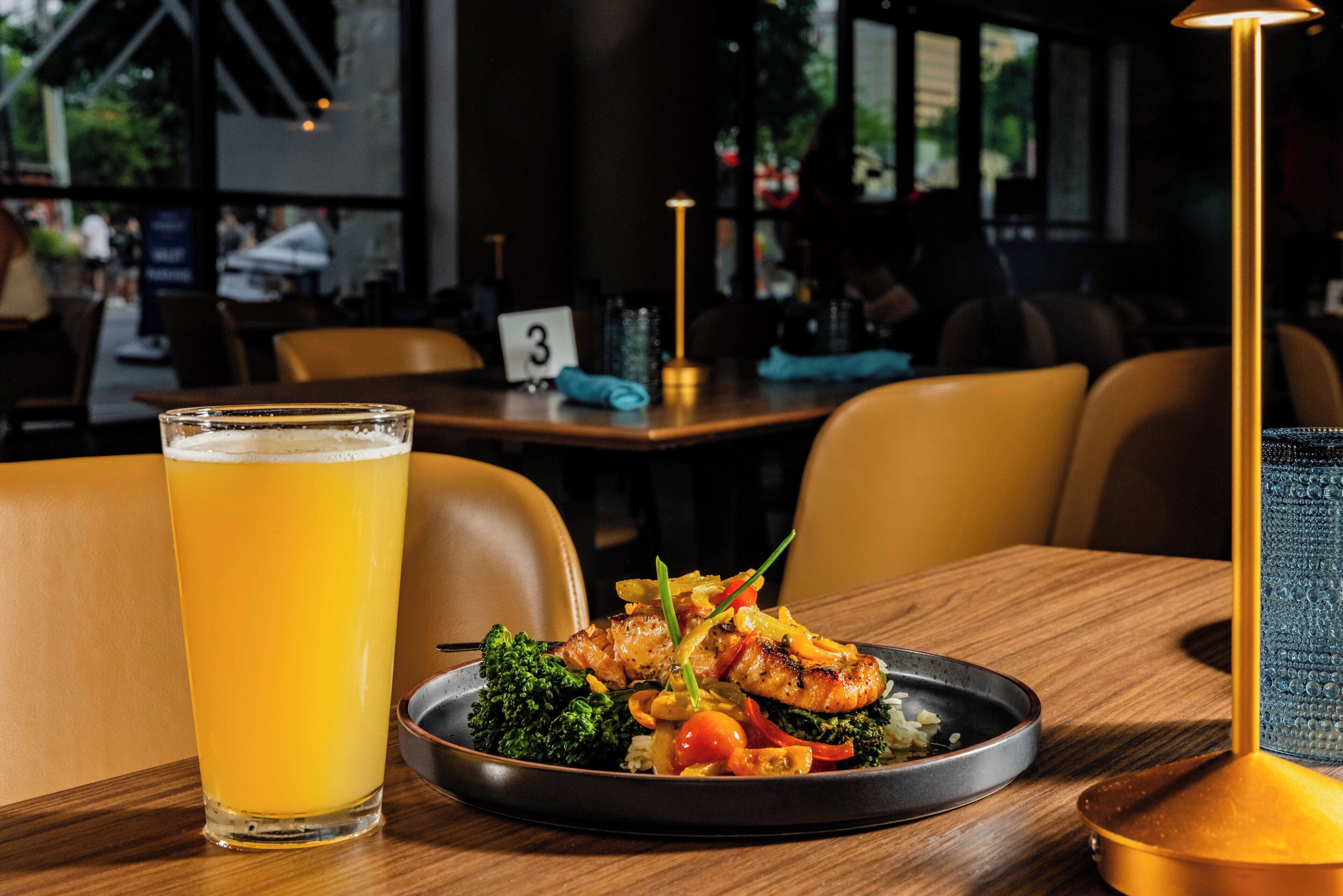 Une table à manger avec une assiette de nourriture, un verre de bière et une bougie.