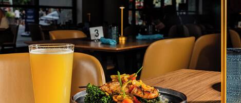 Une table à manger avec une assiette de nourriture, un verre de bière et une bougie.