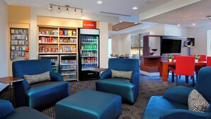 A hotel lobby with seating areas, a vending machine, and a television.