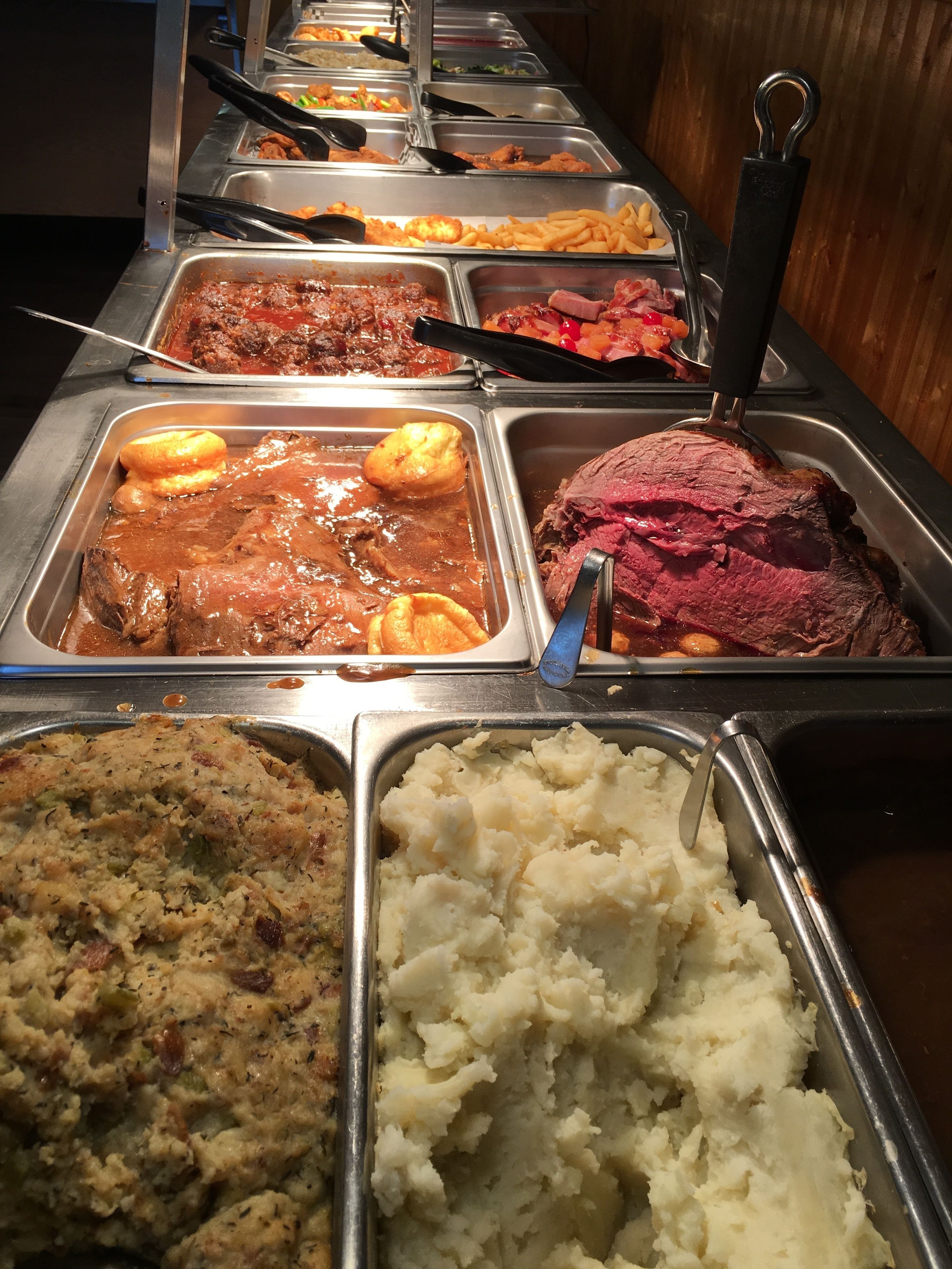 A buffet with various dishes including meat, mashed potatoes, and other side dishes.