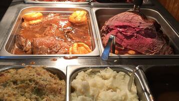 A buffet with various dishes including meat, mashed potatoes, and other side dishes.