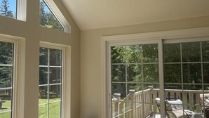 A room with large windows and a sliding glass door leading to an outdoor deck.