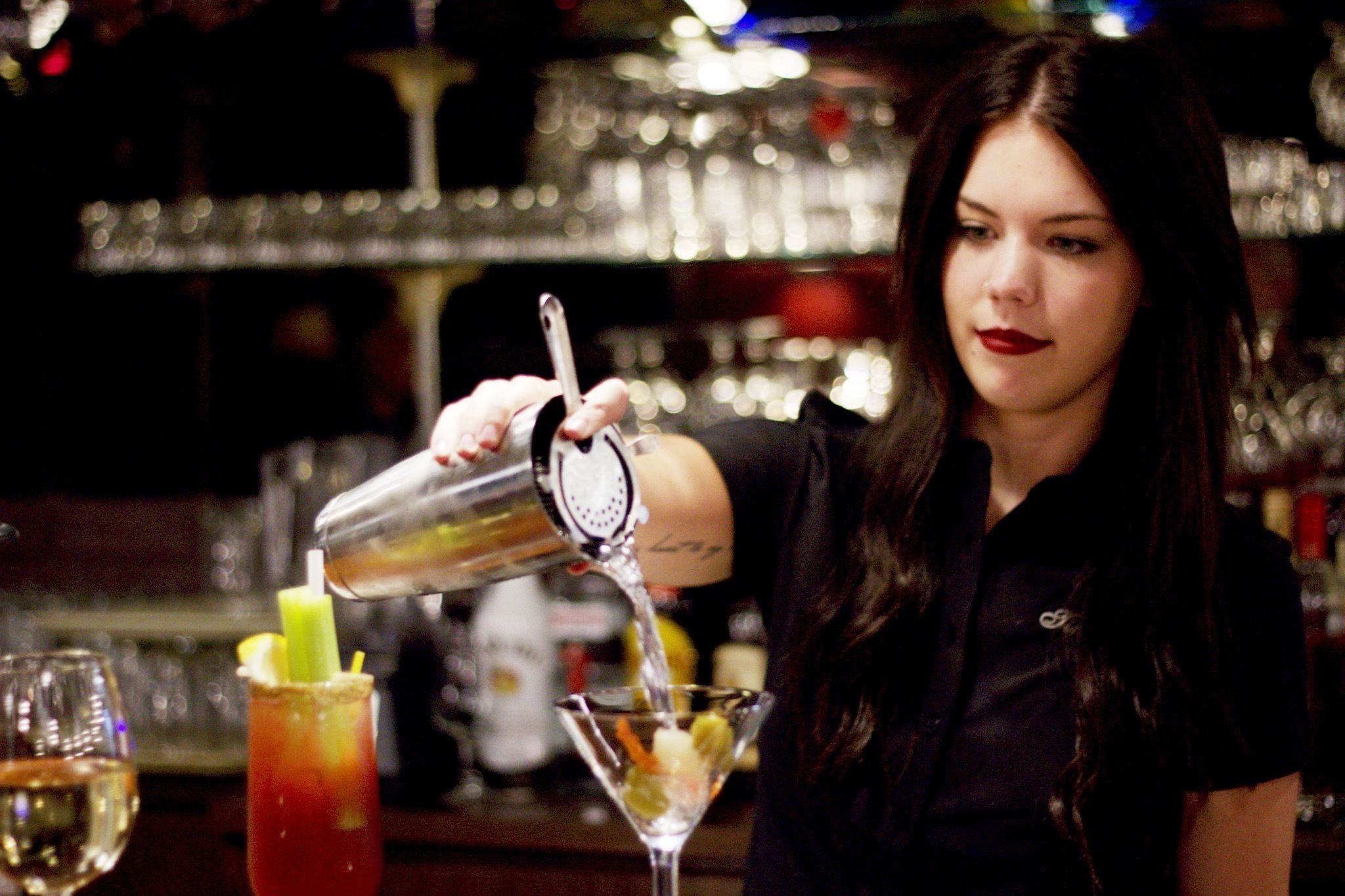 Un barman sirviendo una bebida en una copa de martini.