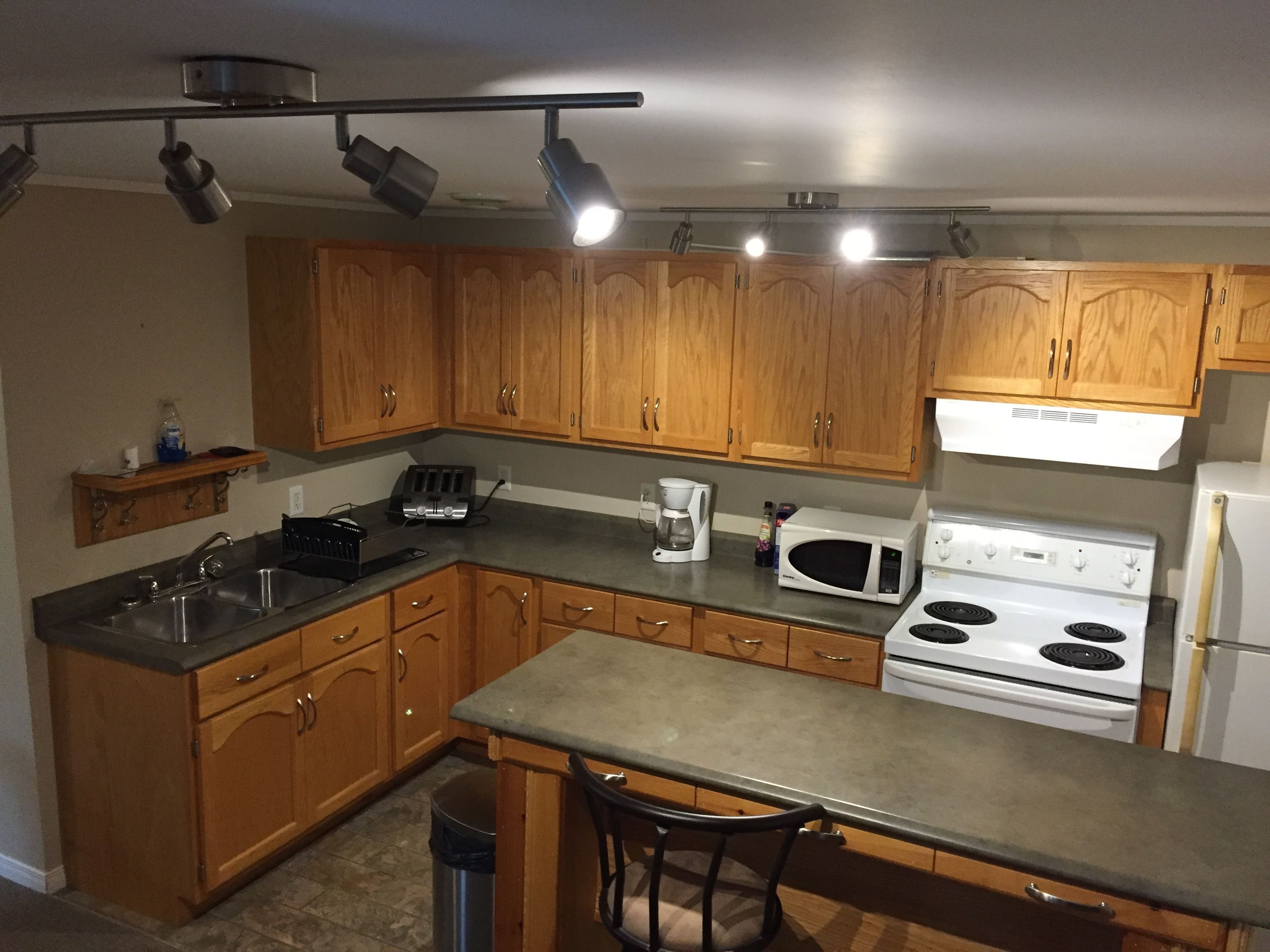 A kitchen with wooden cabinets, a stainless steel sink, a stove, and a microwave.