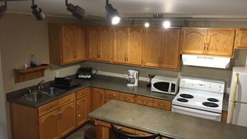 A kitchen with wooden cabinets, a stainless steel sink, a stove, and a microwave.