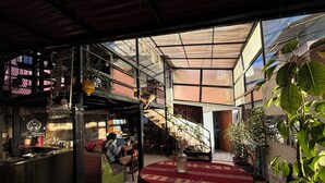 A spacious indoor area with a high ceiling, a staircase, and a seating area with a table and chairs. - Inkas Garden Apartment (Cusco)