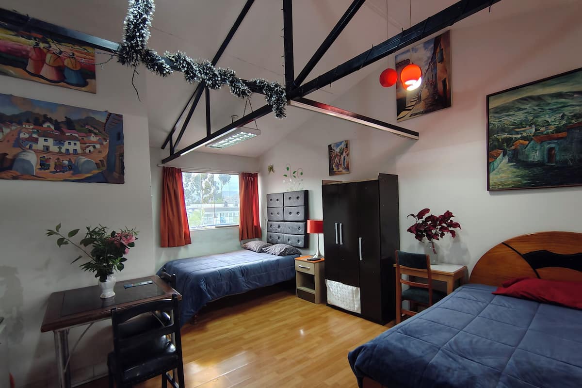 Une chambre avec deux lits, un bureau, une armoire et une fenêtre avec des rideaux.