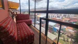 A balcony with a red patterned sofa and a potted plant. - Inkas Garden Apartment (Cusco)