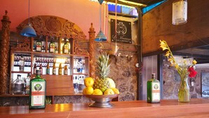 A bar area with a wooden counter, bottles of liquor, a bowl of fruit, and a vase with flowers. - Inkas Garden Apartment (Cusco)
