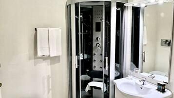 Ein modernes Badezimmer mit einer gläsernen Duschkabine, einem weißen Waschbecken und einer Toilette.