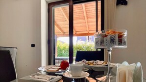 A dining area with a glass table, a white cup, a red apple, and a clear view of the outdoors through a large window. - Lo Scrigno B&B (Montemiletto)