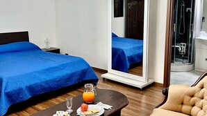 A hotel room with a bed, a chair, a table with breakfast, a mirror, and a shower area. - Lo Scrigno B&B (Montemiletto)