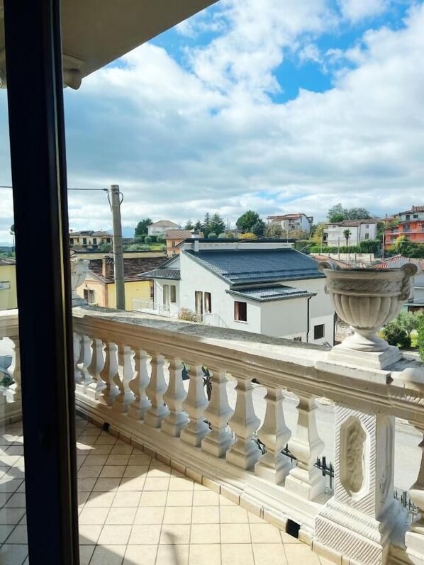 A balcony with a balustrade overlooking a residential area with houses and greenery. - Lo Scrigno B&B (Montemiletto)