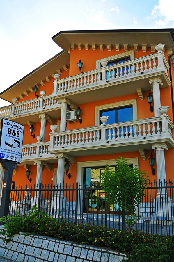 A building with a balcony, a sign for a bed and breakfast, and a fence in front. - Lo Scrigno B&B (Montemiletto)