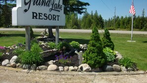 Une enseigne indiquant l’emplacement du Grand Lake Resort, entourée de parterres de fleurs aménagés et d’un drapeau.