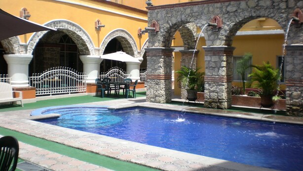 Un patio con piscina, arcos de piedra y mobiliario exterior.