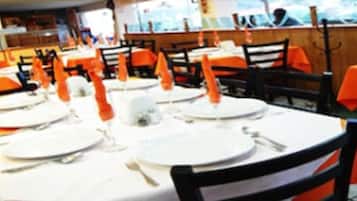 A restaurant with tables set for dining, featuring orange tablecloths and white plates.