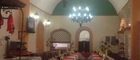 A dining hall with multiple tables, a chandelier, and a tiled floor.