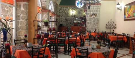 Un restaurante con paredes de piedra, manteles anaranjados y un candelabro.