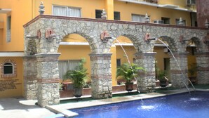 Un edificio con un arco de piedra que da acceso a una zona de piscina.