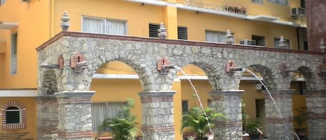 A building with a stone archway leading to a pool area.