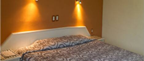 A bedroom with a bed, a nightstand, and two wall-mounted lights.