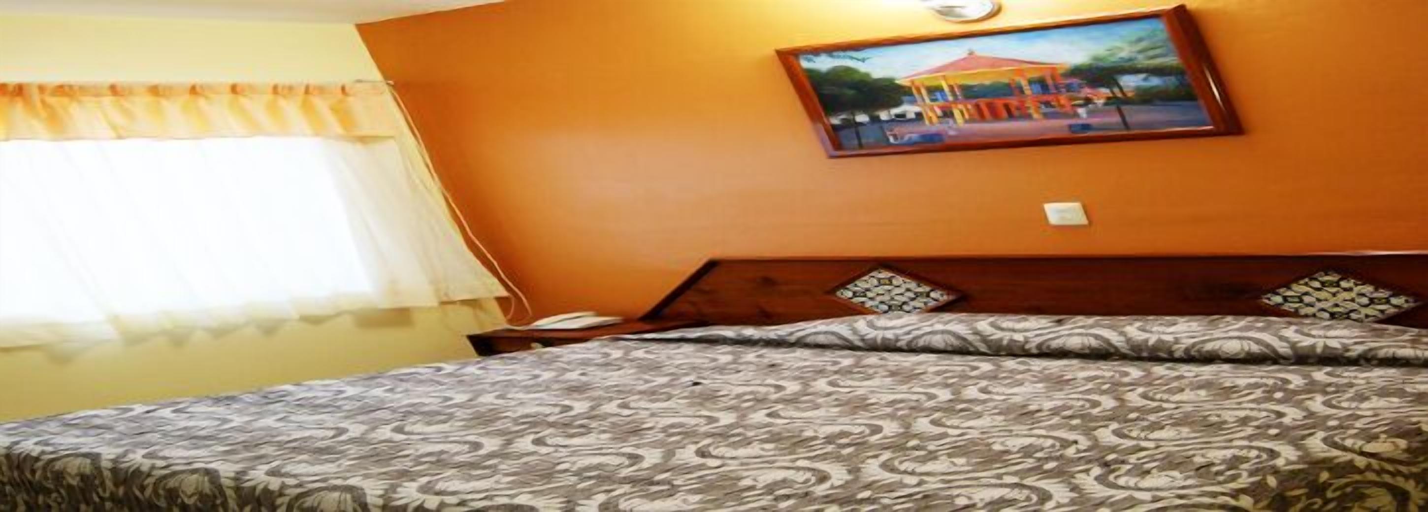 Una habitación de hotel con una cama, una mesita de noche y un cuadro en la pared.